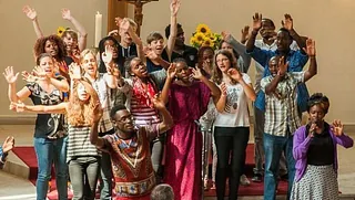Eine Gruppe Menschen steht vor dem Altar in der Kirche Rüdersdorf und schaut fröhlich in die Kamera