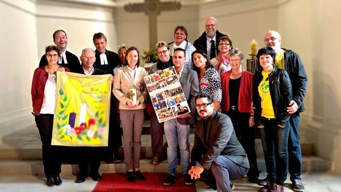 Eine Gruppe Menschen steht vor dem Altar in der Kirche Rüdersdorf und schaut fröhlich in die Kamera